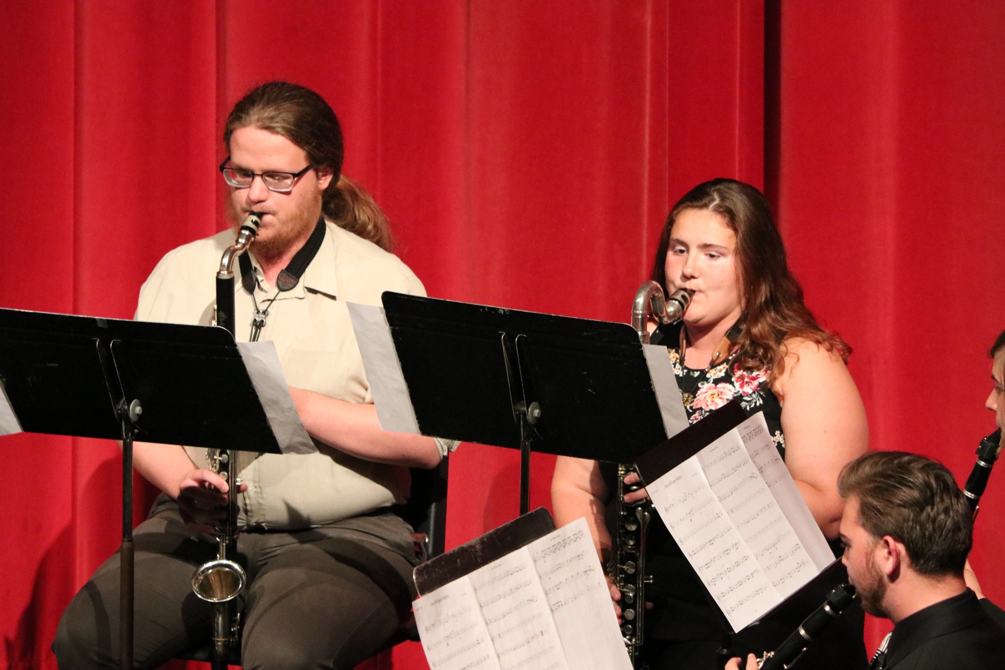 Seth and Myrtle playing alto and bass clarinet, respectively, in front of a red curtain